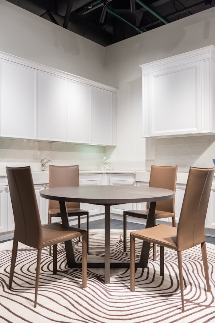 Contemporary kitchen with round table and chairs, featuring minimalist design and neutral tones.