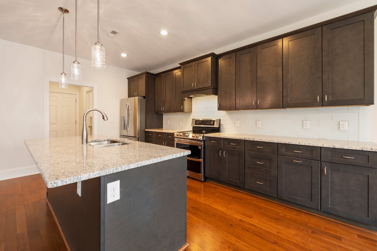home-hero Spacious modern kitchen featuring a granite island, stainless steel appliances, and hardwood floors.