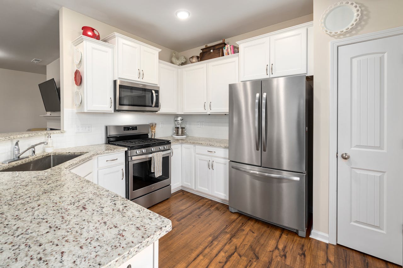 services-02 Bright modern kitchen featuring white cabinets and stainless steel appliances, including a refrigerator and stove.